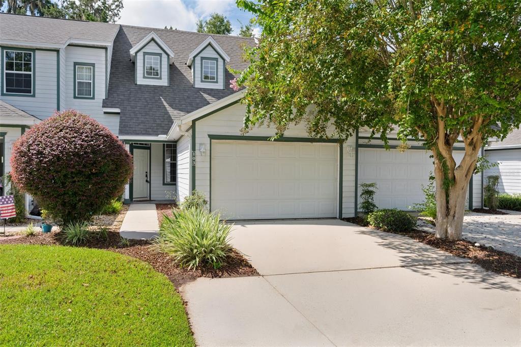 A two-story townhouse with a white garage, green trim, and a small front yard — 231 NE 28TH AVENUE UNIT 103, OCALA, FL