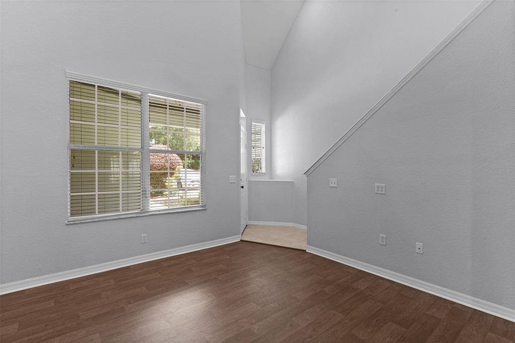 A room with high ceilings, wood-look flooring, a large window, and a staircase — 231 NE 28TH AVENUE UNIT 103, OCALA, FL