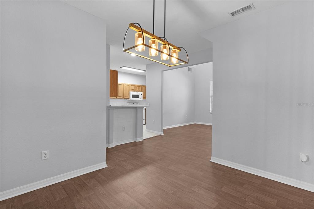 A dining area with a wood-look floor and a rectangular pendant light fixture — 231 NE 28TH AVENUE UNIT 103, OCALA, FL