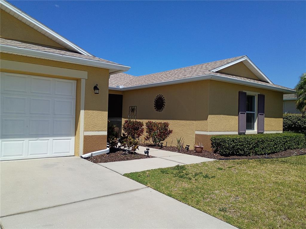 A single-story house with a yellow stucco exterior, a white garage door, and a walkway — 5220 BUTTERFLY SHELL DRIVE, APOLLO BEACH, FL