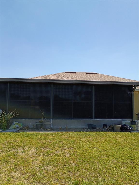 A screened-in porch with a shingled roof sits above a concrete base in a yard — 5220 BUTTERFLY SHELL DRIVE, APOLLO BEACH, FL