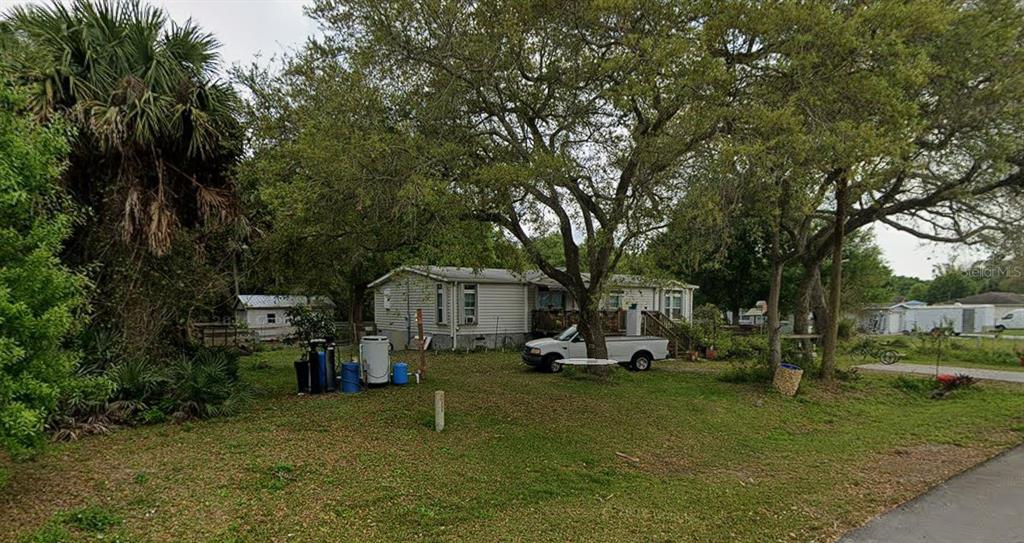 A single-story mobile home sits on a grassy lot with mature trees and a truck — 3926 NW 39TH AVENUE, OKEECHOBEE, FL