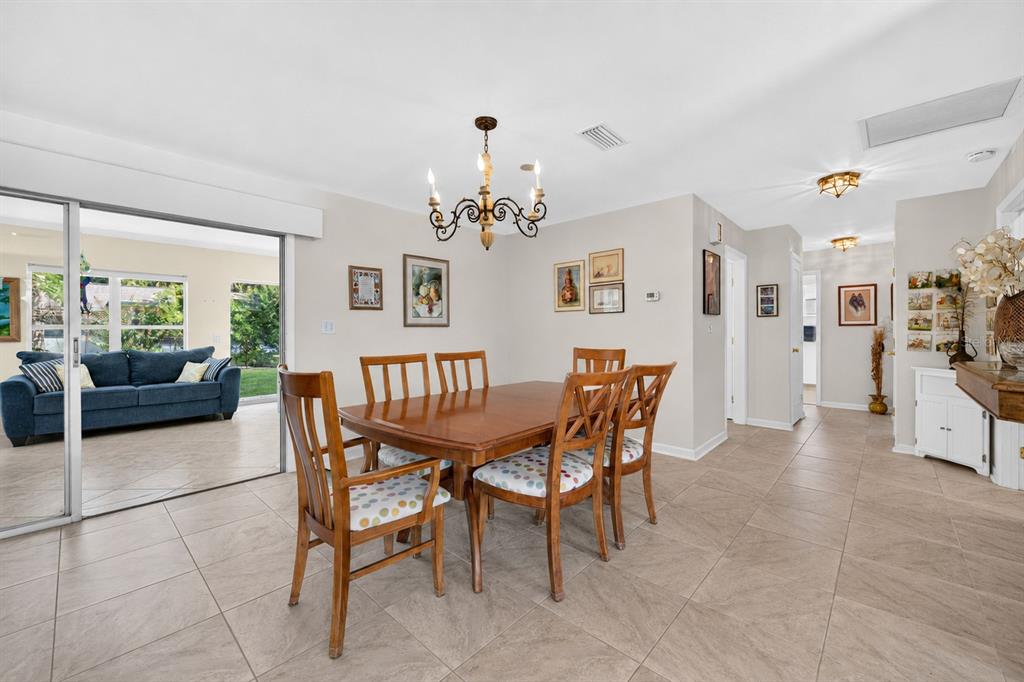 A dining room with a wooden table and chairs, tile flooring, and a sliding glass door — 802 SANDWEDGE DRIVE, NEW SMYRNA BEACH, FL