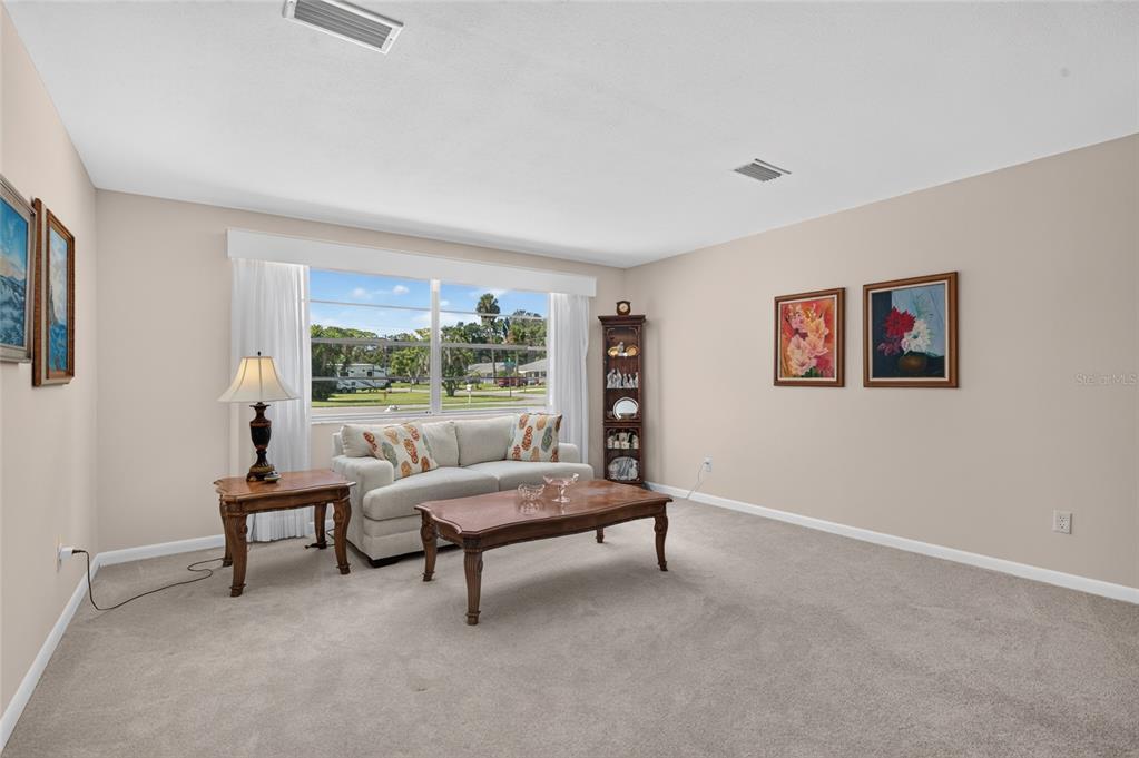 A living room features a beige sofa, wooden coffee table, and framed wall art — 802 SANDWEDGE DRIVE, NEW SMYRNA BEACH, FL