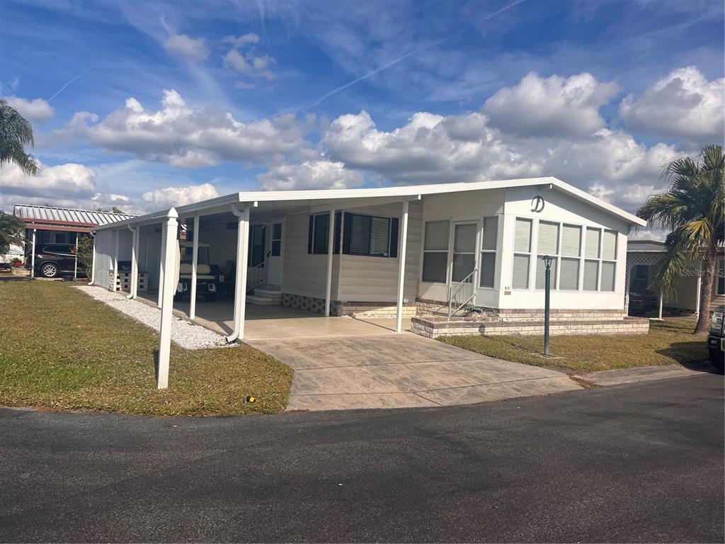 A single-story manufactured home with a white exterior, a carport, and a concrete driveway — 5316 53RD AVENUE E UNIT M15, BRADENTON, FL