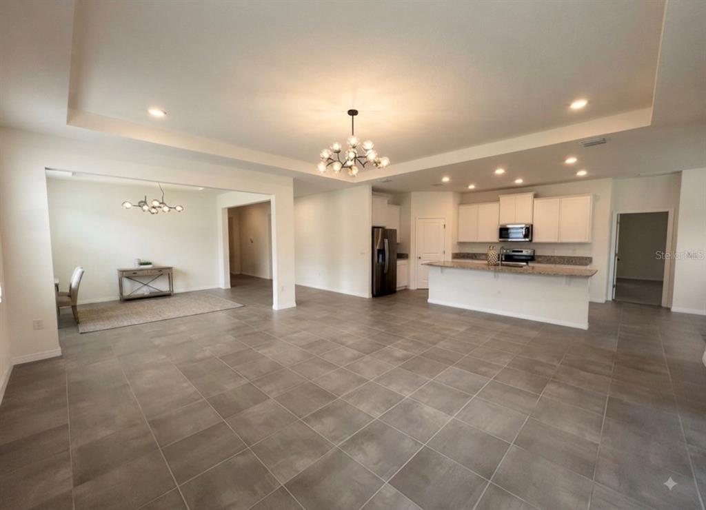 An open-concept kitchen and dining area features tile flooring, a kitchen island, and recessed lighting — 5811 SW 80TH LANE, OCALA, FL