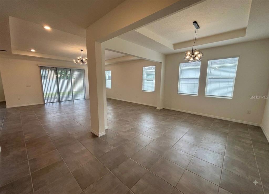 An open-concept living area features large neutral floor tiles, recessed lighting, and two modern chandeliers — 5811 SW 80TH LANE, OCALA, FL