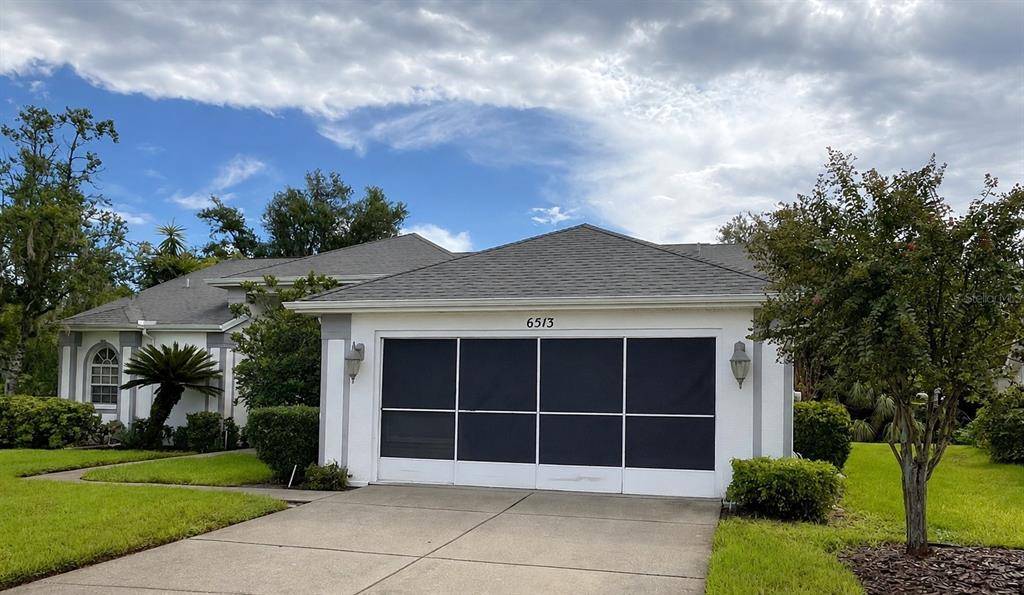 A single-story house with a white exterior, a screened garage door, and a concrete driveway — 6513 CARDINAL CREST DRIVE, NEW PORT RICHEY, FL