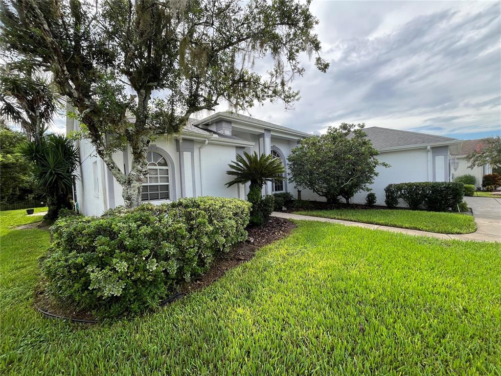 A white house with gray trim, arched windows, and a landscaped front yard — 6513 CARDINAL CREST DRIVE, NEW PORT RICHEY, FL