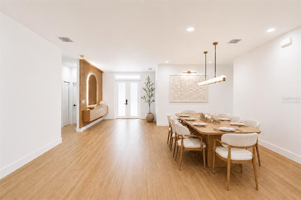 A dining room features a long wooden table, white chairs, and a modern light fixture — 6308 NOTRE DAME TERRACE, NORTH PORT, FL