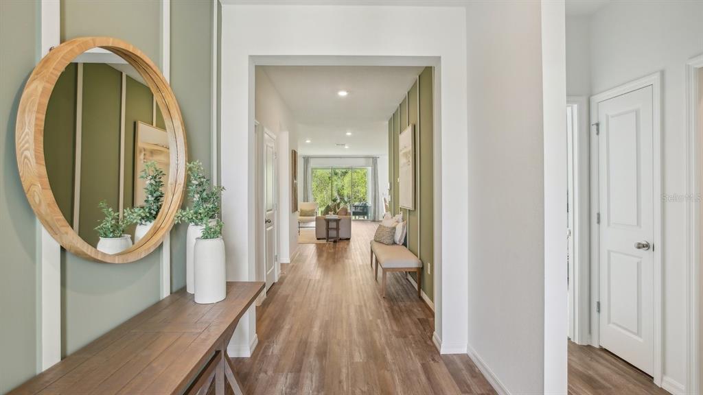 A hallway with wood-look flooring, board and batten walls, a round mirror, and a console table — 32736 WEATHERED OAK DRIVE, WESLEY CHAPEL, FL