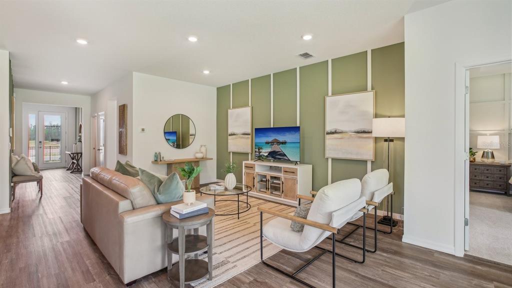 A living room features a green accent wall with white trim, a sofa, and armchairs — 32736 WEATHERED OAK DRIVE, WESLEY CHAPEL, FL