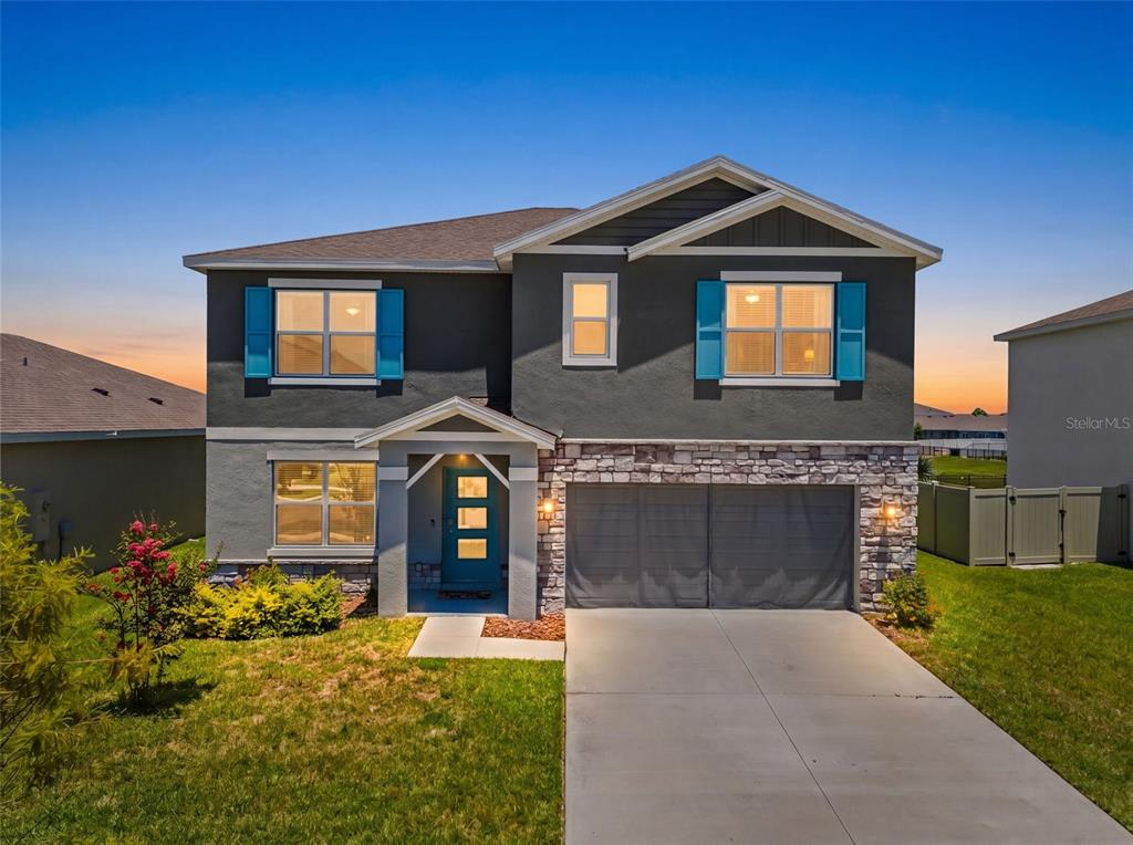 A two-story house with a gray stucco exterior, stone accents, and a two-car garage — 9728 CRESCENT RAY DRIVE, WESLEY CHAPEL, FL