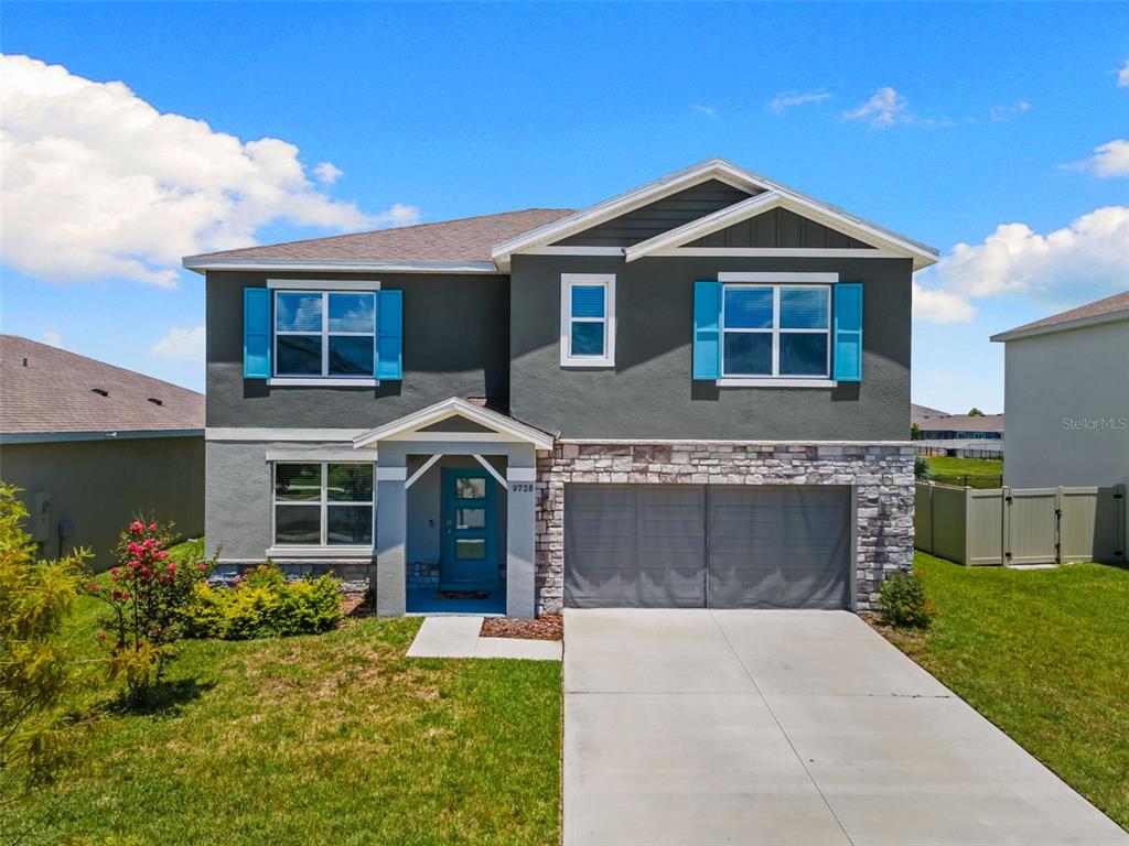 A two-story house with a gray stucco exterior, stone accents, and bright blue shutters — 9728 CRESCENT RAY DRIVE, WESLEY CHAPEL, FL