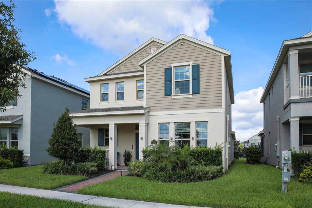 A two-story house with tan siding, a front porch, and a brick walkway — 16625 POINT ROCK DRIVE, WINTER GARDEN, FL