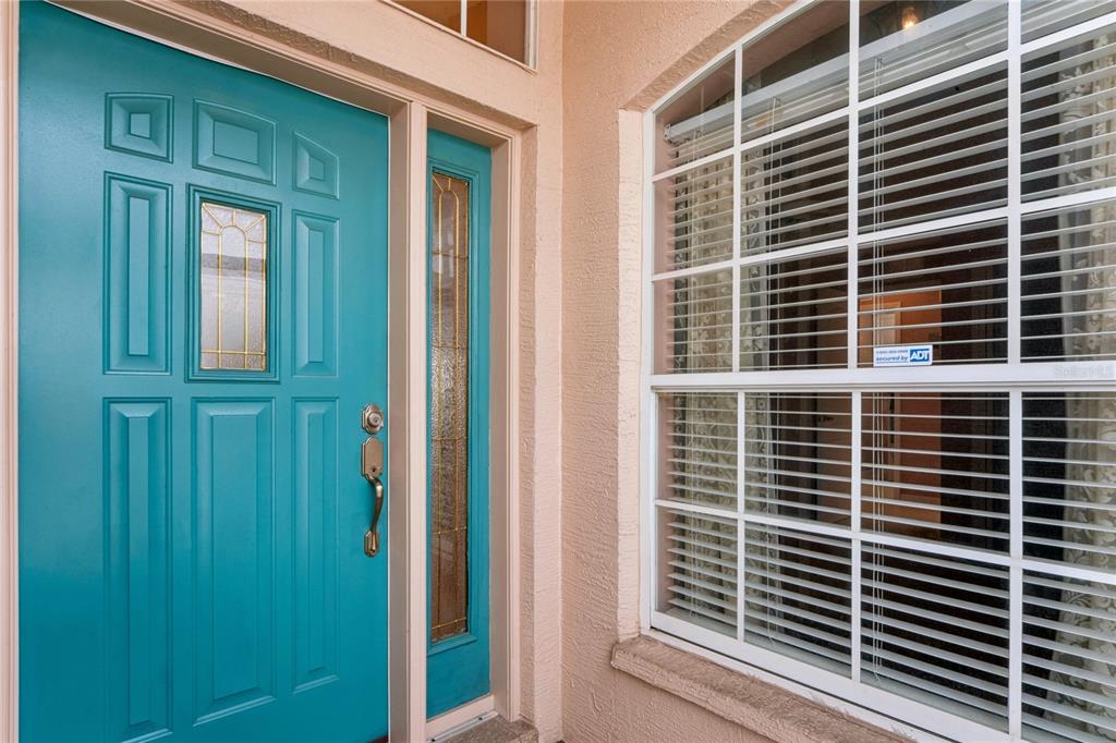 A concrete walkway leads between two stucco walls toward a white door and landscaping — 312 ROYAL PALM WAY, SPRING HILL, FL