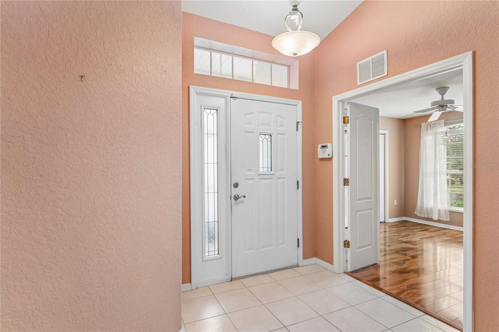 A teal front door with a side light window sits next to a white-framed window — 312 ROYAL PALM WAY, SPRING HILL, FL