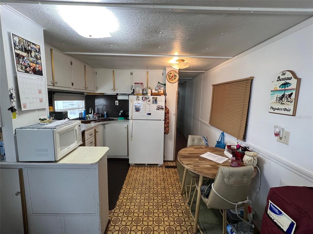 A kitchen with white cabinets, a white refrigerator, a round dining table, and patterned flooring — 12674 SEMINOLE BOULEVARD UNIT C30, LARGO, FL