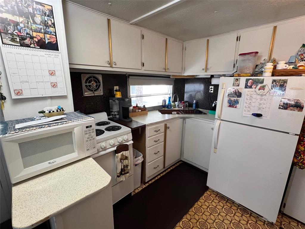 A kitchen features white cabinets, a white stove, a white refrigerator, and patterned floor tiles — 12674 SEMINOLE BOULEVARD UNIT C30, LARGO, FL