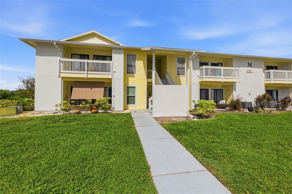A two-story yellow apartment building with white balconies and a concrete walkway — 455 ALT 19 S UNIT 218, PALM HARBOR, FL