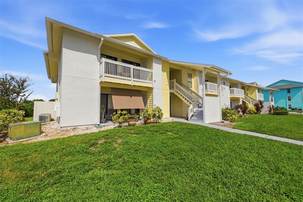 A two-story apartment building with yellow siding, a balcony, and an exterior staircase — 455 ALT 19 S UNIT 218, PALM HARBOR, FL