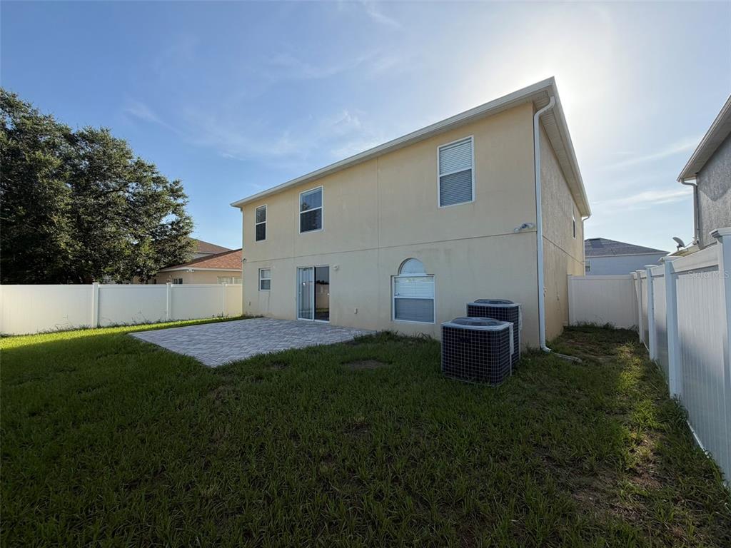 The rear exterior of a two-story house features a paved patio and two air conditioning units — 247 BLAKE AVENUE, DAVENPORT, FL