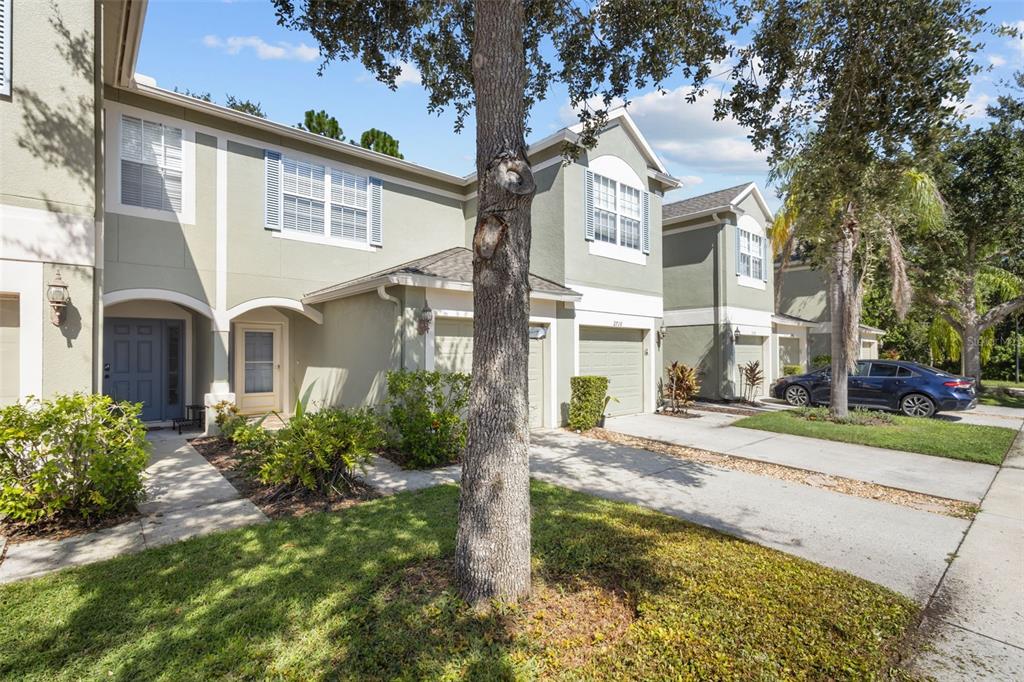 A row of two-story townhouses with light green stucco siding, attached garages, and paved driveways — 2712 CONCH HOLLOW DRIVE, BRANDON, FL