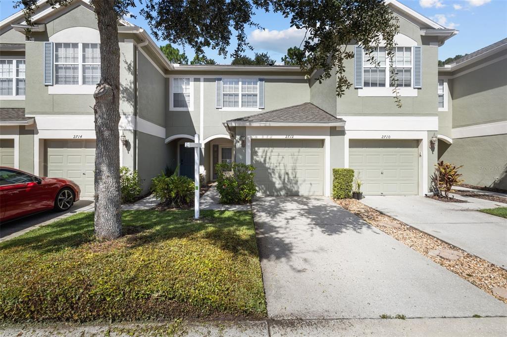 A row of three attached townhouses with light green stucco siding and beige garage doors — 2712 CONCH HOLLOW DRIVE, BRANDON, FL