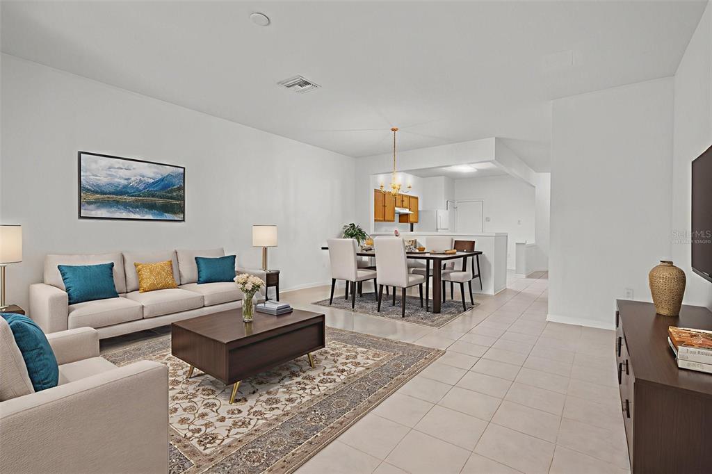 A living room and dining area with tile floors, neutral walls, and virtual staging — 2712 CONCH HOLLOW DRIVE, BRANDON, FL
