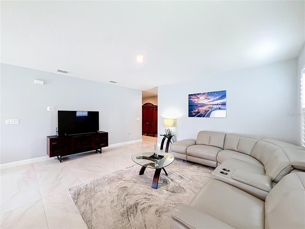 A living room features a beige sectional sofa, a glass coffee table, and tile flooring — 3628 SAPPHIRE HOLLOW WAY, FORT PIERCE, FL