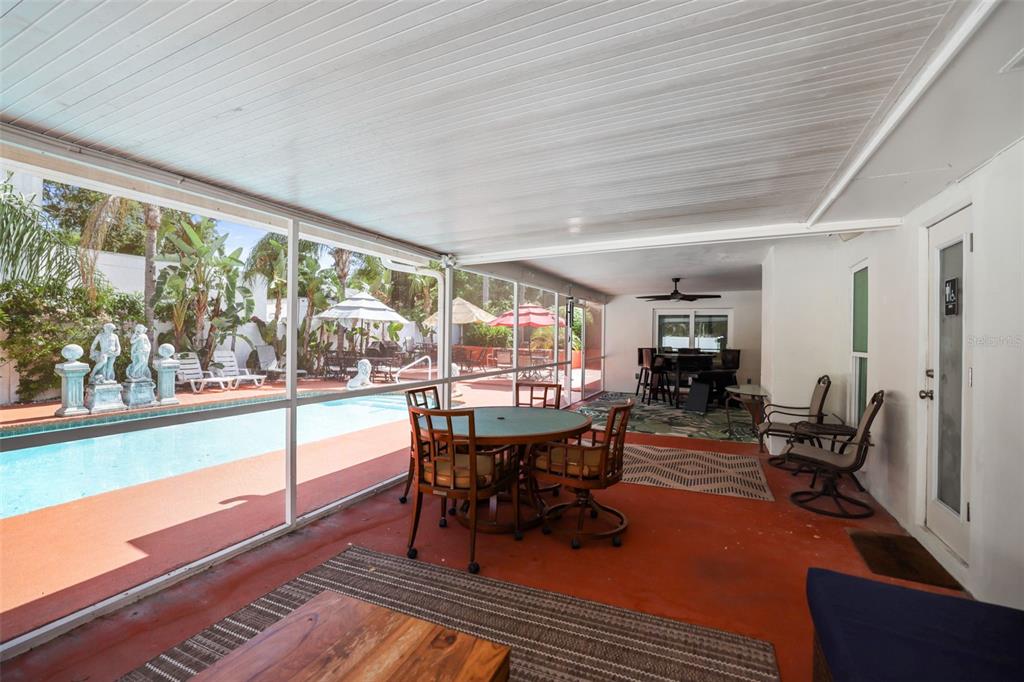 A screened-in patio features a dining set, outdoor furniture, and a view of a pool — 1981 CASTILLE DRIVE, DUNEDIN, FL