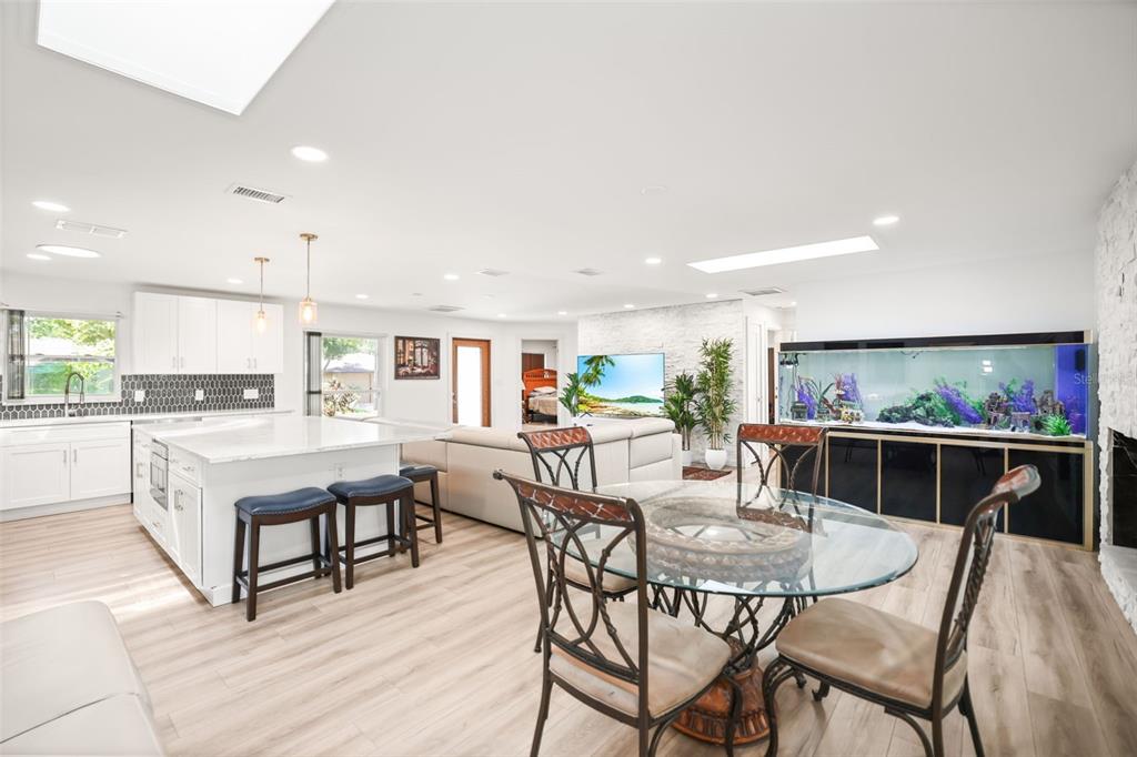 An open-concept kitchen and living area features a large aquarium, island seating, and light flooring — 1981 CASTILLE DRIVE, DUNEDIN, FL