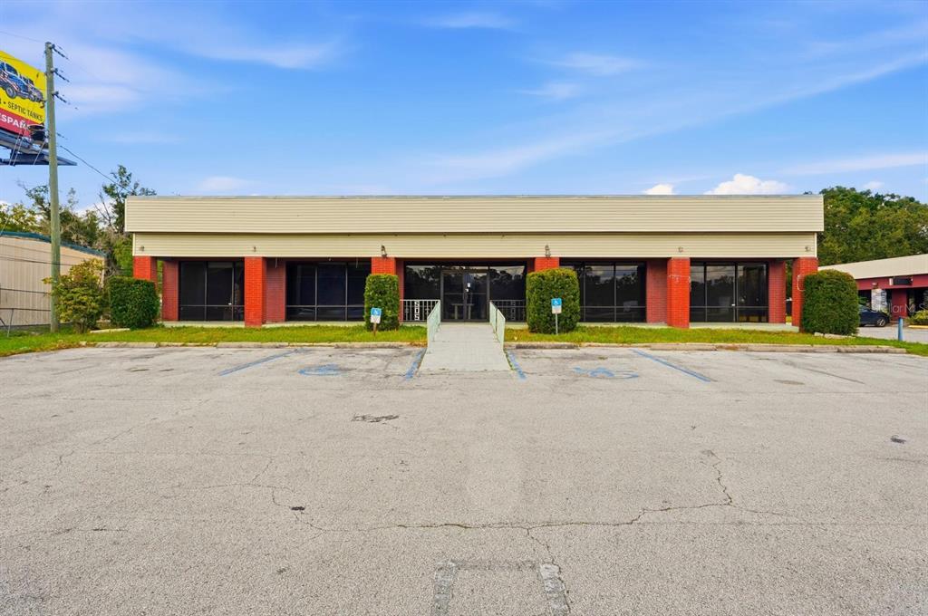 A single-story commercial building with a beige facade, red brick accents, and a paved parking lot — 4830 US HIGHWAY 92 E, LAKELAND, FL