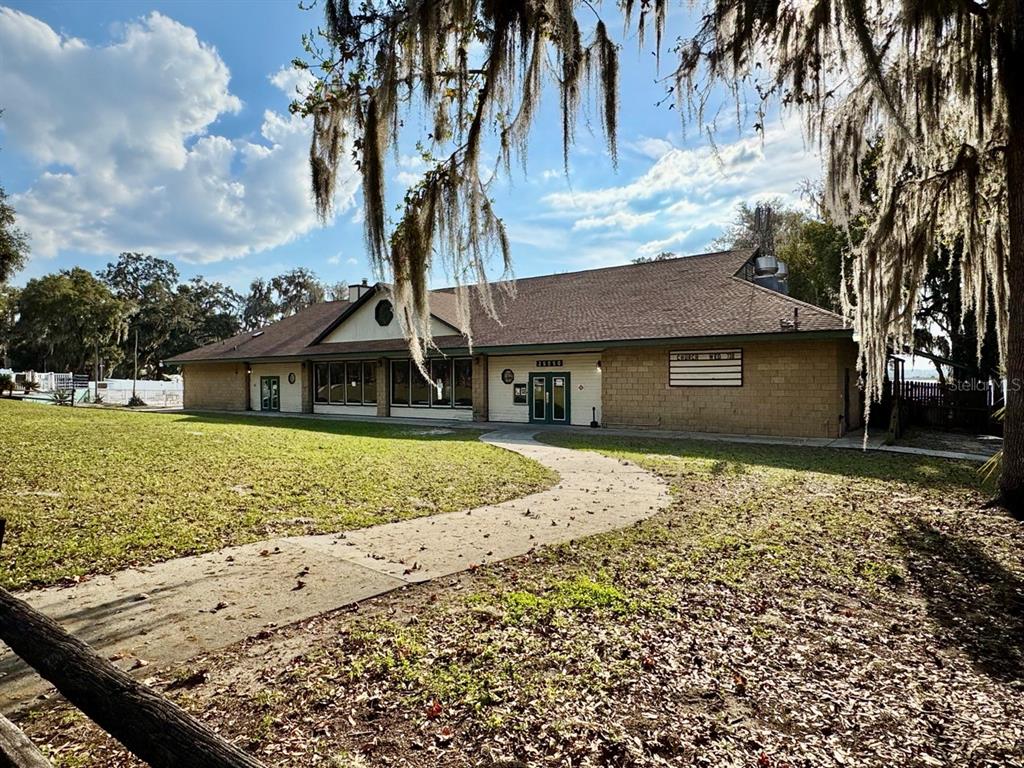 A single-story building with a tan brick facade and a brown shingled roof — 25225 NE 141ST LANE NE, SALT SPRINGS, FL