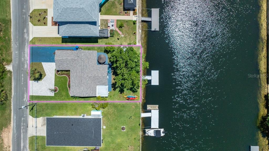 An aerial view shows a waterfront house with a backyard, dock, and boat on water — 4117 TAMPICO TRAIL, HERNANDO BEACH, FL