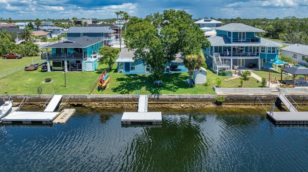An aerial view shows three waterfront houses with private docks along a canal — 4117 TAMPICO TRAIL, HERNANDO BEACH, FL