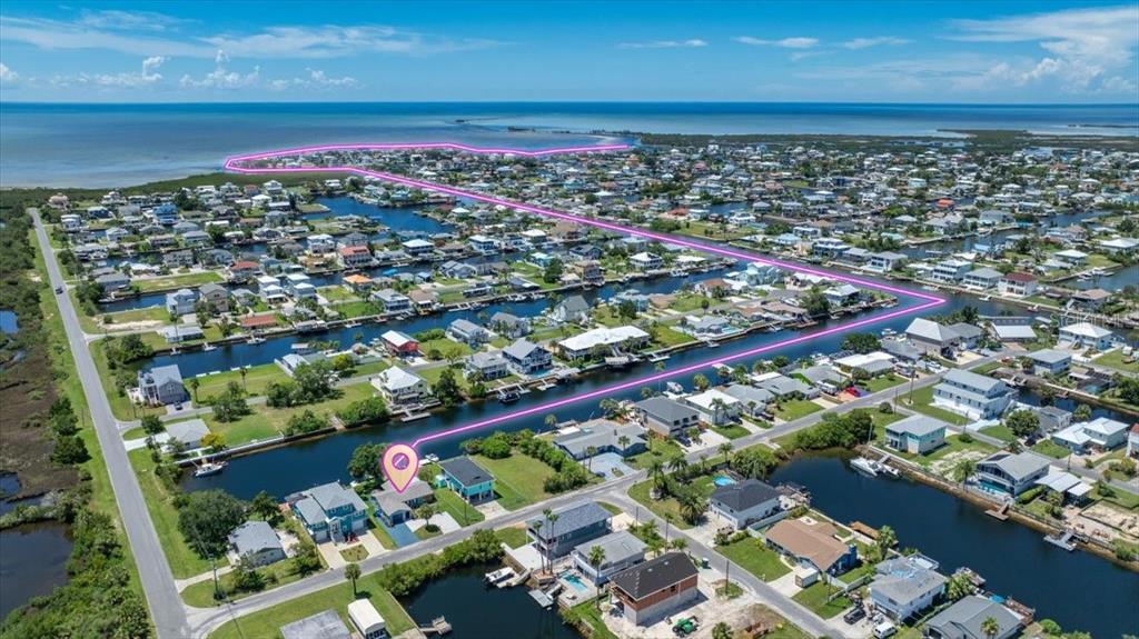 An aerial view shows a coastal neighborhood with houses, canals, and a highlighted property boundary — 4117 TAMPICO TRAIL, HERNANDO BEACH, FL