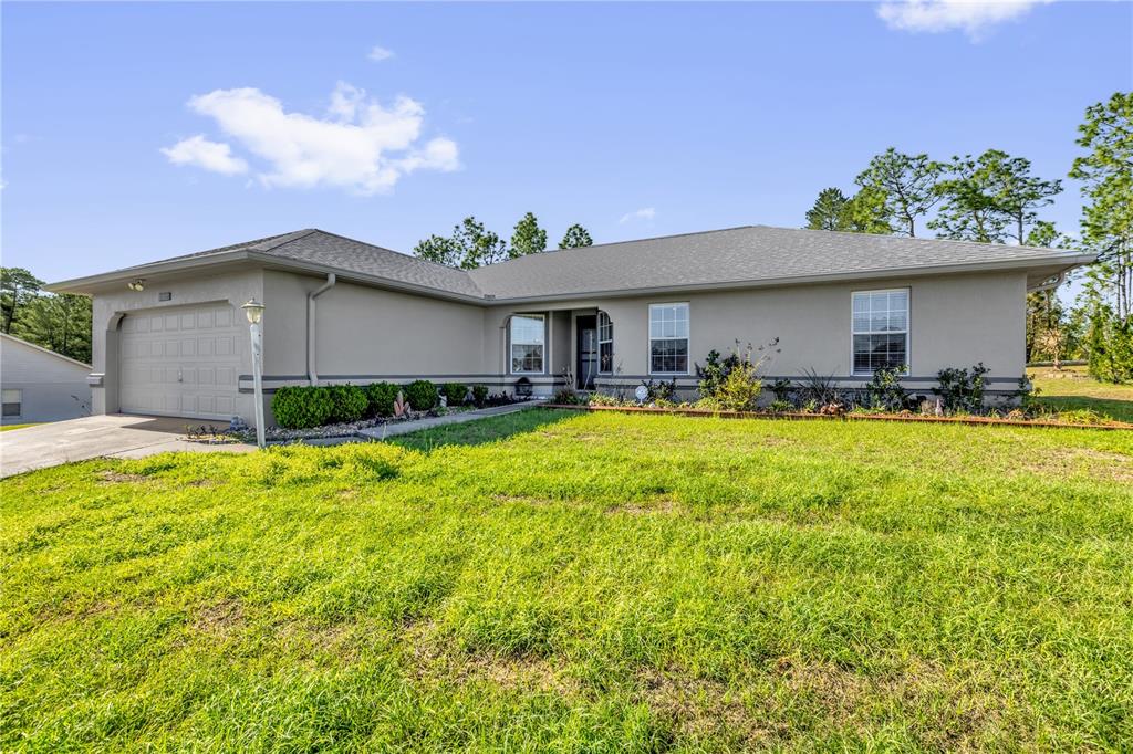 A kitchen with white cabinets, dark countertops, and a dining area in the background — 8506 SW 136TH LOOP, OCALA, FL