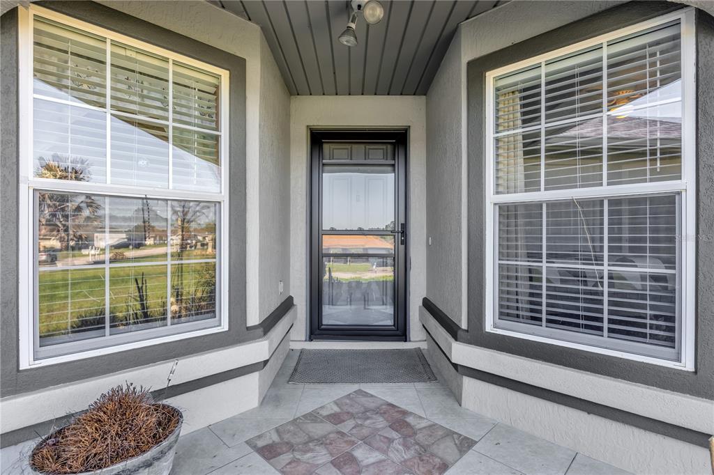 A kitchen with a breakfast bar, white cabinets, and dark countertops opens to an entryway — 8506 SW 136TH LOOP, OCALA, FL