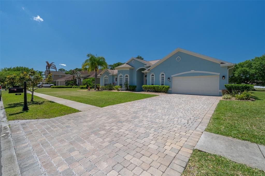 A light blue single-story house features a paved driveway and a two-car garage — 230 RIDGEMONT CIRCLE, PALM BAY, FL