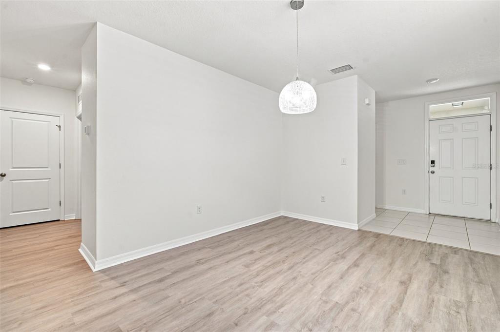 An empty dining area features light wood-look flooring, white walls, and a modern pendant light — 10920 CARLTON FIELDS DRIVE, RIVERVIEW, FL