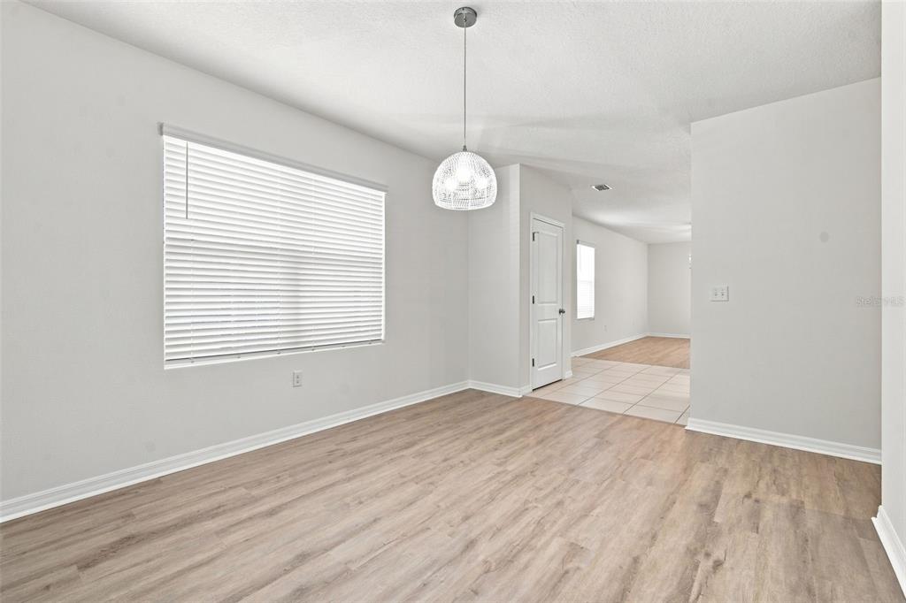 A dining area with light wood-look flooring, a pendant light, and a window with blinds — 10920 CARLTON FIELDS DRIVE, RIVERVIEW, FL