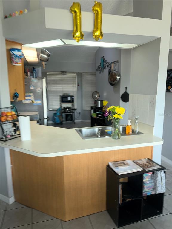 A kitchen features a peninsula counter with a sink, light wood cabinetry, and gold balloons — 1499 COURTLAND BOULEVARD, DELTONA, FL