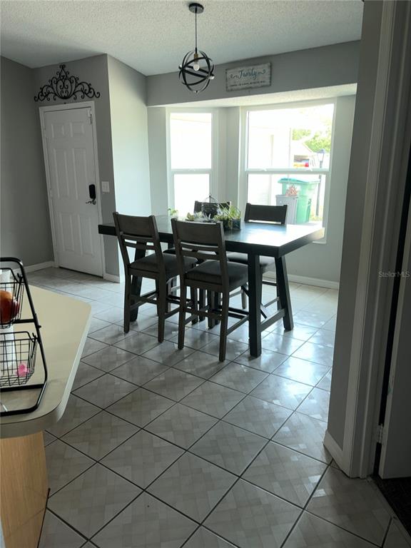 A dining area with a dark wood table, four chairs, tile flooring, and large windows — 1499 COURTLAND BOULEVARD, DELTONA, FL