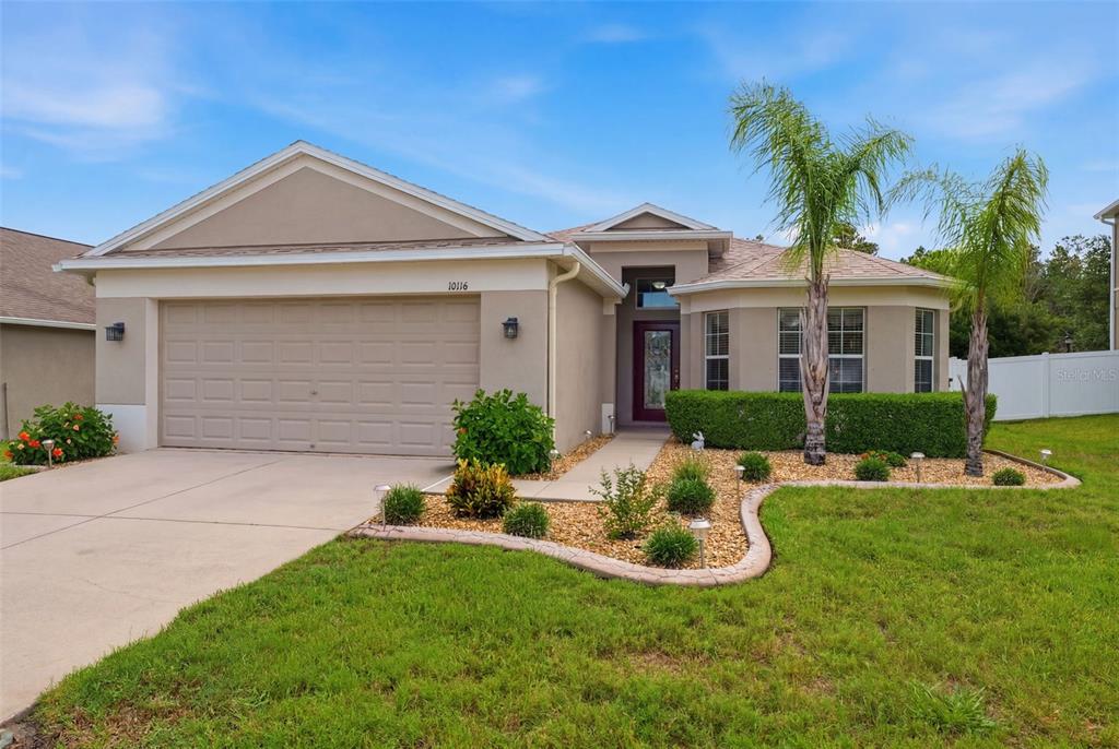 A single-story house with a beige stucco exterior, two palm trees, and a concrete driveway — 10114 IVES LOOP, HUDSON, FL