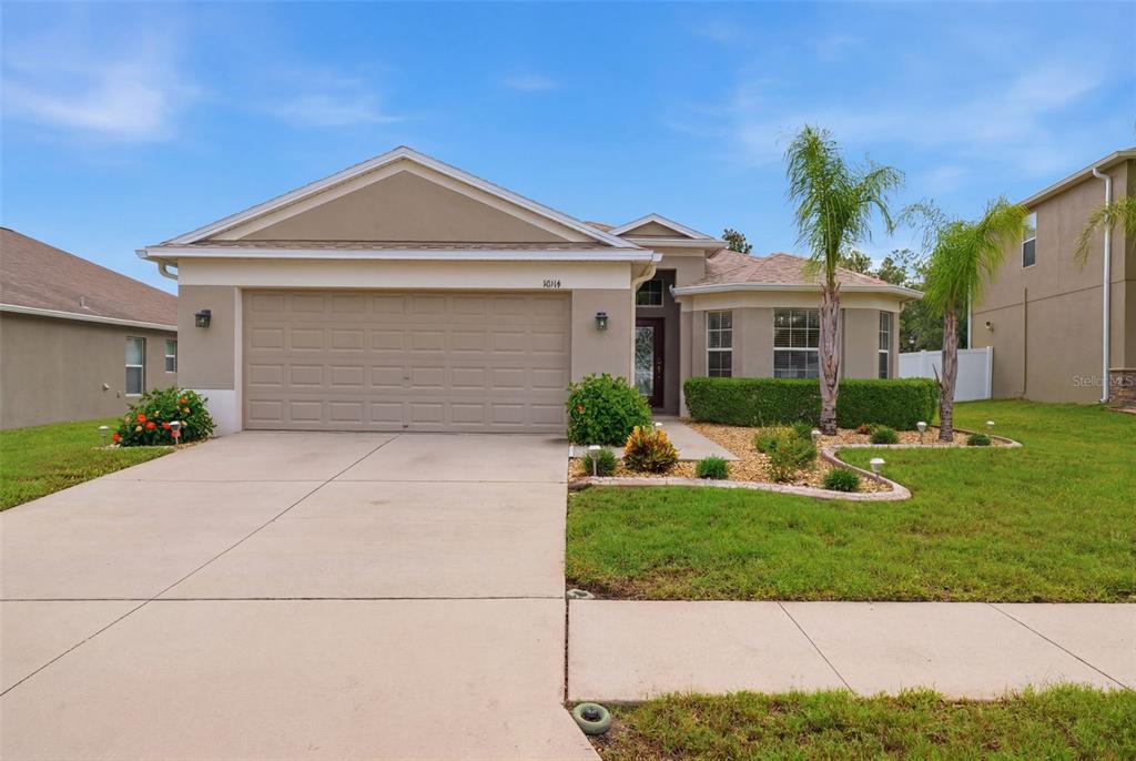 A single-story house with a beige stucco exterior, a two-car garage, and a palm tree — 10114 IVES LOOP, HUDSON, FL