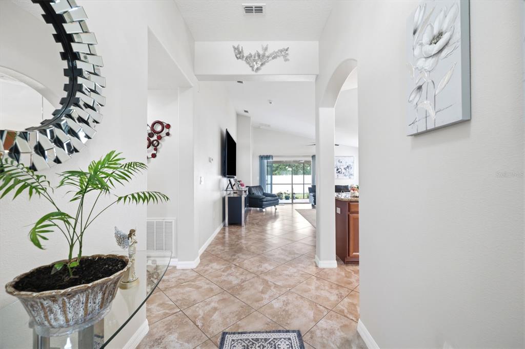 A tiled entryway leads into a living area with a view of a screened patio — 10114 IVES LOOP, HUDSON, FL