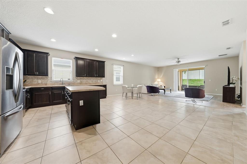 An open-concept kitchen with dark cabinets and an island flows into a living area — 20945 OLDENBURG LOOP, MOUNT DORA, FL