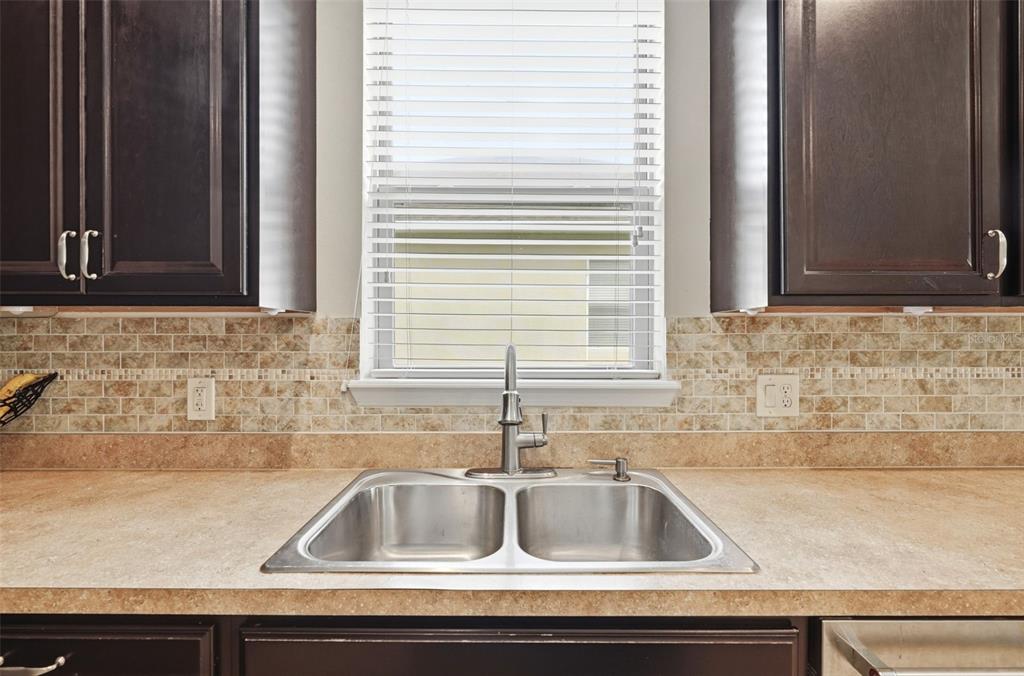 A kitchen sink with a stainless steel faucet sits below a window with blinds — 20945 OLDENBURG LOOP, MOUNT DORA, FL