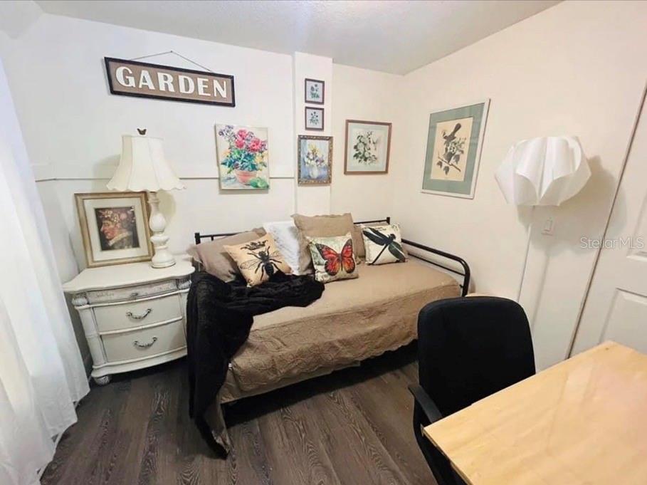 A bedroom features a daybed, a white nightstand with a lamp, and various wall art — 1121 ORANGE AVENUE, DUNEDIN, FL